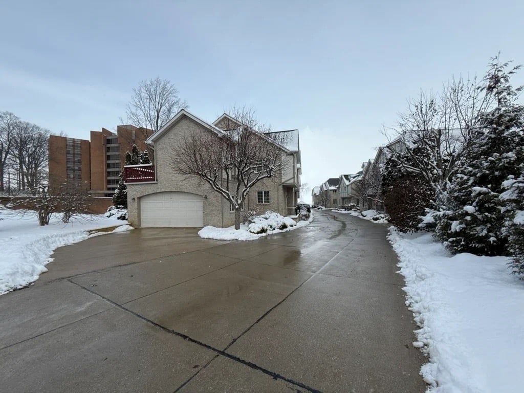 Snow-covered townhouse driveway and sidewalks after winter snow removal in a residential community