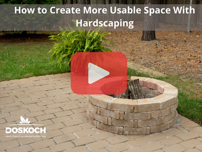 Fire pit. Red play buttom overlay and Doskoch logo. Words: How to Create More Usable Space With Hardscaping.
