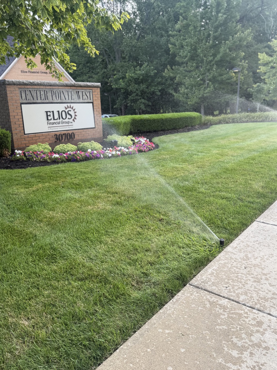 Commercial irrigation system watering a landscaped lawn and flower beds outside a business property