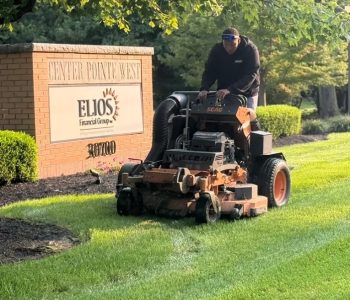 Commercial-Lawn Mowing Landscaping crew mowing grass near the Center Pointe West sign on a commercial property